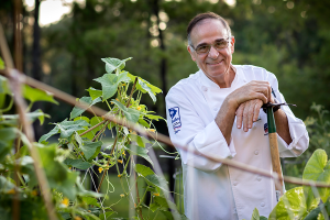 Chef Jean Portrait leaning on a hoe in a vegetable garden