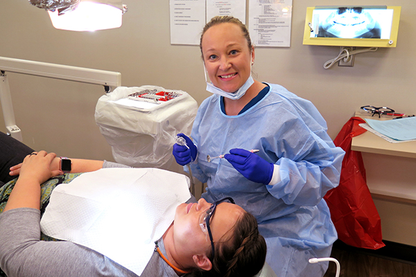 Dental Hygiene student in PPE sits with patient
