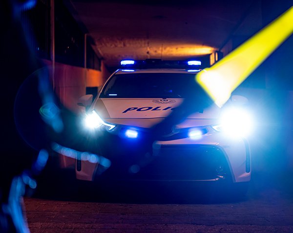 Police car at night with headlights, person holding direction light