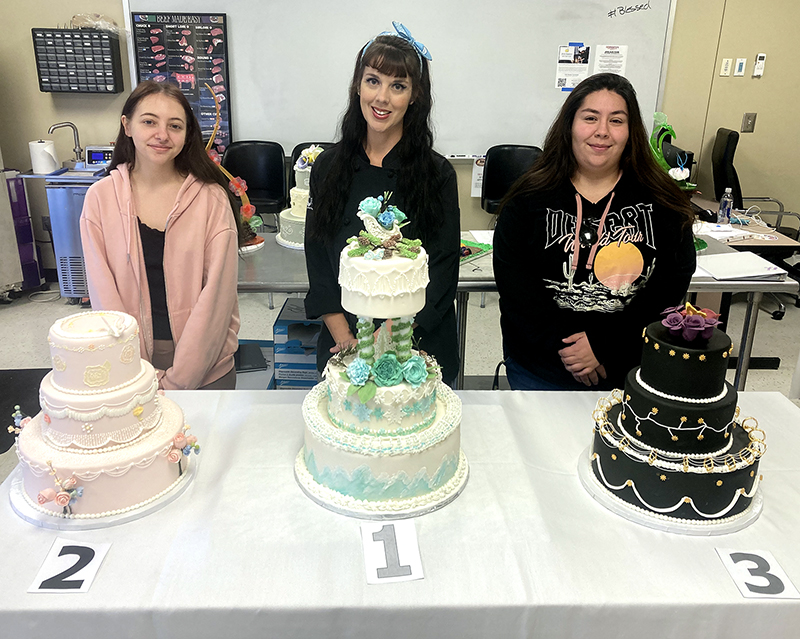 Student standing with three-tier wedding cakes (finals)