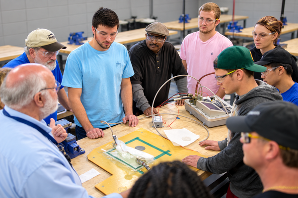 several aviation students watching the instructor guide a hands on lesson