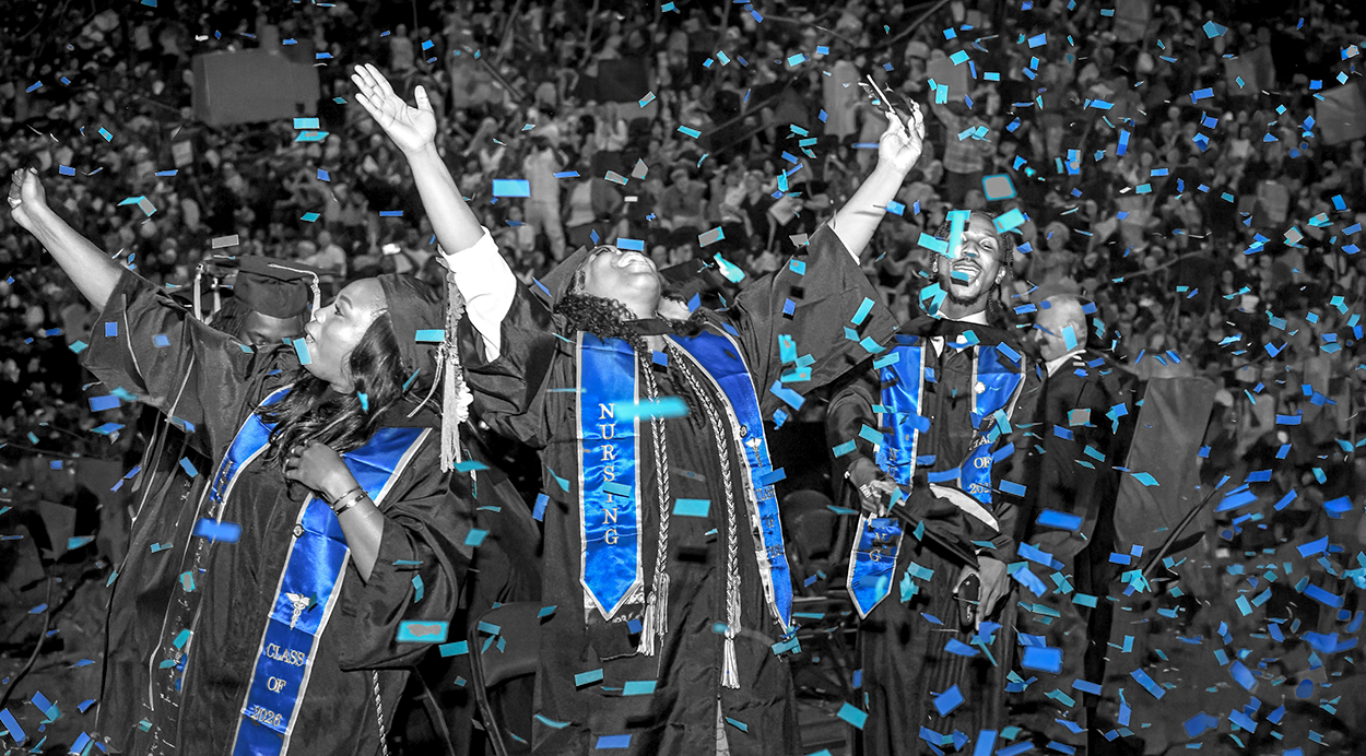 Savannah Tech graduates celebrating their graduation as blue confetti falls all around.